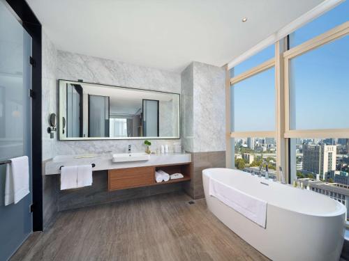 a bathroom with a tub and a sink and a mirror at Hilton Garden Inn Hangzhou Xixi Zijingang in Hangzhou