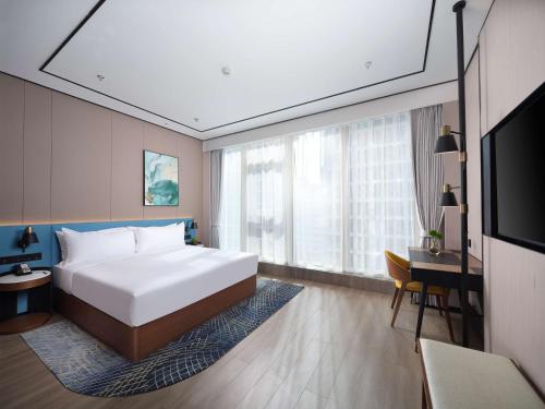 a bedroom with a bed and a desk and a television at Hilton Garden Inn Hangzhou Xixi Zijingang in Hangzhou