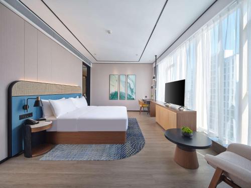a hotel room with a bed and a tv at Hilton Garden Inn Hangzhou Xixi Zijingang in Hangzhou