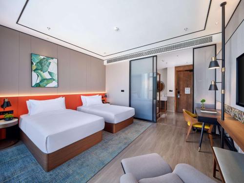 a hotel room with two beds and a living room at Hilton Garden Inn Hangzhou Xixi Zijingang in Hangzhou