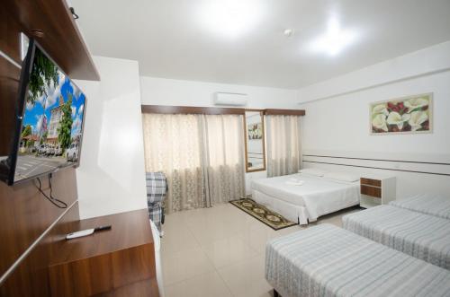 a hotel room with two beds and a flat screen tv at Hotel Penha in Penha