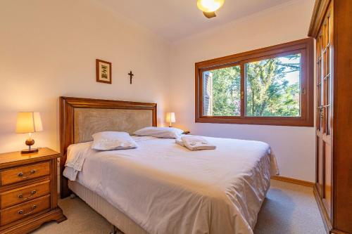 a bedroom with a large bed and a window at Villagio de Fiore - Stay House Temporada in Gramado