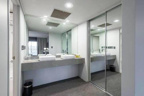 a bathroom with two sinks and two mirrors at DoubleTree by Hilton Alice Springs in Alice Springs