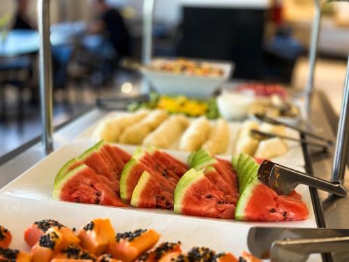 um prato de melancia e outros alimentos num buffet em Hotel Gran Vivenzo Belo Horizonte em Belo Horizonte
