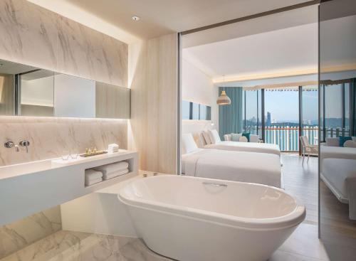 a white bathroom with a tub and a bedroom at Hilton Pattaya in Pattaya