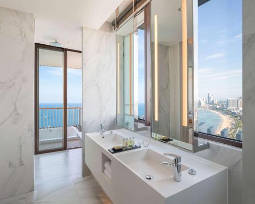 a bathroom with a sink and a large mirror at Hilton Pattaya in Pattaya Central