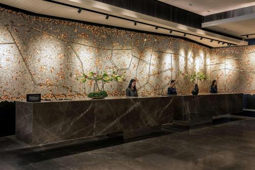 three women standing at a wall with plants on it at DoubleTree by Hilton Bangkok Ploenchit in Bangkok