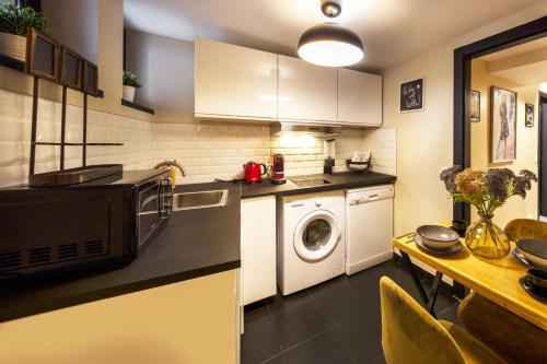 une cuisine avec un lave-linge et un micro-ondes dans l'établissement Appartement entier Strasbourg Centre, à Strasbourg