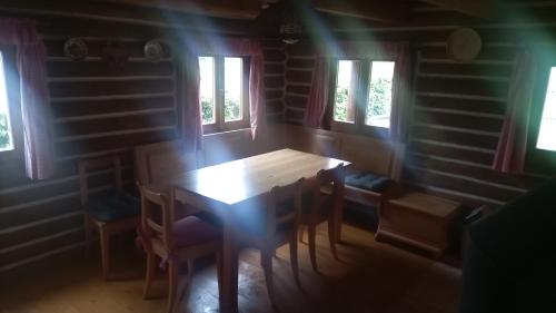 un tavolo in legno con sedie in una stanza con finestre di Srub Rtyně a Rtyně v Podkrkonoší