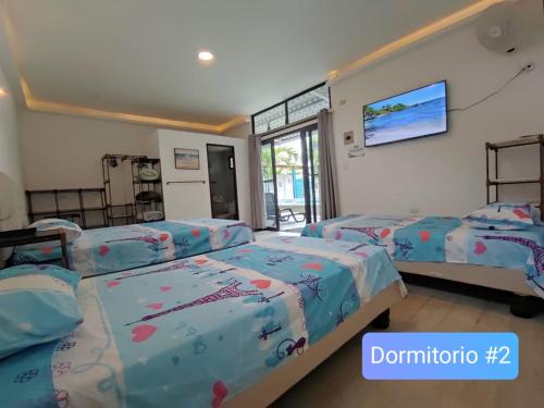 a bedroom with three beds and a flat screen tv at Casa Halley #2 con vista al mar , Playas in Data de Posorja