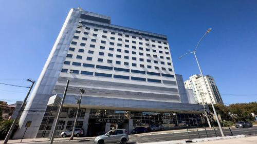 a large building with a car parked in front of it at Hotel Gran Vivenzo Belo Horizonte in Belo Horizonte