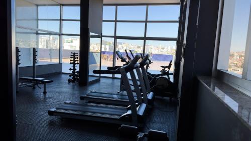 a gym with cardio equipment in a large room with windows at Hotel Gran Vivenzo Belo Horizonte in Belo Horizonte