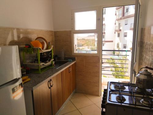 uma cozinha com um lavatório, uma janela e um fogão em Appartement sur la route de la plage de Achakar em Tânger