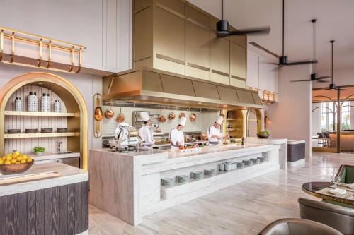 a kitchen with three chefs preparing food in it at Waldorf Astoria Bangkok in Bangkok