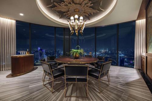 a dining room with a chandelier and a table and chairs at Waldorf Astoria Bangkok in Bangkok