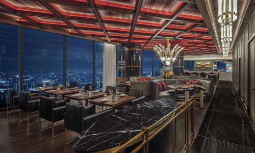 a restaurant with tables and chairs and a view of the city at Waldorf Astoria Bangkok in Bangkok