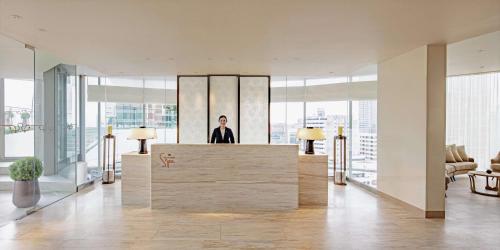 a man standing behind a counter in a lobby at Waldorf Astoria Bangkok in Bangkok