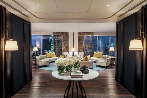 a living room with couches and a table with flowers at Waldorf Astoria Bangkok in Bangkok