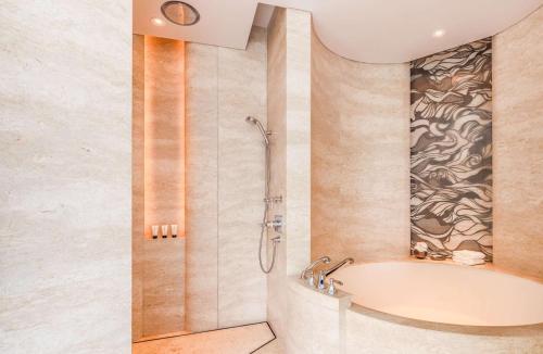 a bathroom with a shower and a bath tub at Waldorf Astoria Bangkok in Bangkok