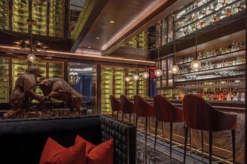 a bar with a statue of two dogs and wine bottles at Waldorf Astoria Bangkok in Bangkok