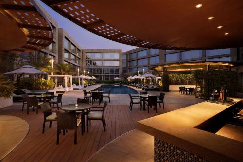 an outdoor patio with tables and chairs and a pool at Hilton Bangalore Embassy GolfLinks in Bengaluru