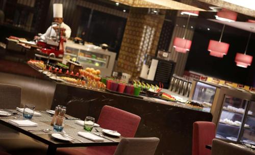 a restaurant with a table and a chef in the kitchen at Hilton Bangalore Embassy GolfLinks in Bengaluru