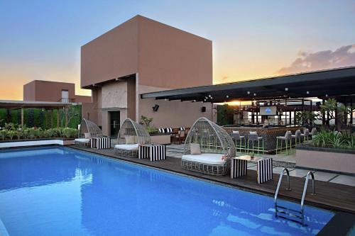 une piscine avec des chaises longues et un bâtiment dans l'établissement DoubleTree Suites by Hilton Bengaluru Outer Ring Road, à Bangalore
