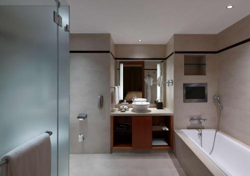 a bathroom with a tub and a sink and a bath tub at Hilton Bangalore Embassy GolfLinks in Bangalore