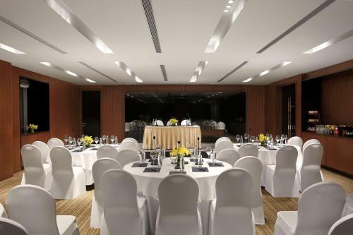 a banquet hall with white tables and white chairs at Hilton Bangalore Embassy GolfLinks in Bengaluru