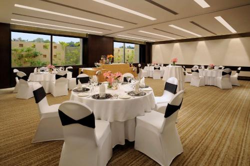 a banquet room with white tables and white chairs at Hilton Bangalore Embassy GolfLinks in Bengaluru