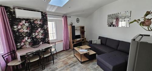 uma sala de estar com um sofá e uma mesa em Appartement Kantar - Tout en Rose em Anduze