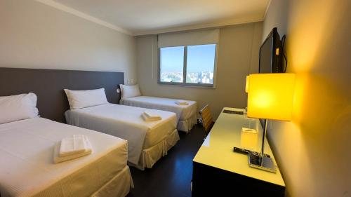 a hotel room with two beds and a window at Hotel Gran Vivenzo Belo Horizonte in Belo Horizonte