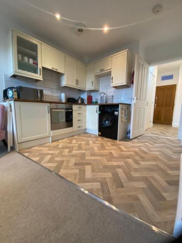 uma cozinha com armários brancos e piso em madeira em Fabulous Flat close to Town & Countryside, Matlock em Matlock