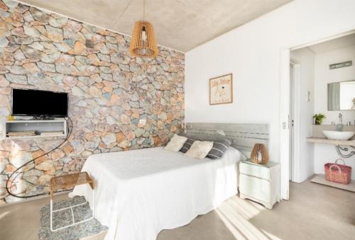 a bedroom with a stone wall with a bed at Luminoso y comfortable monoambienteA 25 minutos de Ezeiza in Remedios de Escalada