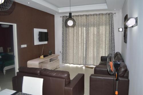 a living room with a leather couch and a television at Apartment No 18 - West Terraces in Flic-en-Flac