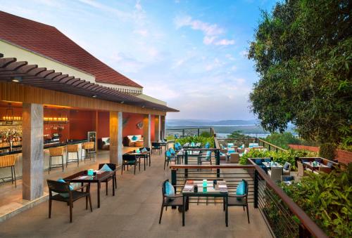 a restaurant with tables and chairs on a balcony at DoubleTree by Hilton Goa - Panaji in Panaji