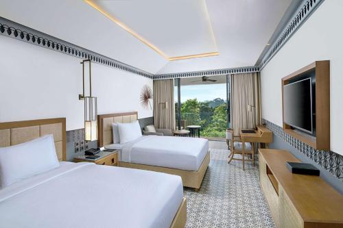 a hotel room with two beds and a flat screen tv at DoubleTree by Hilton Goa - Panaji in Panaji
