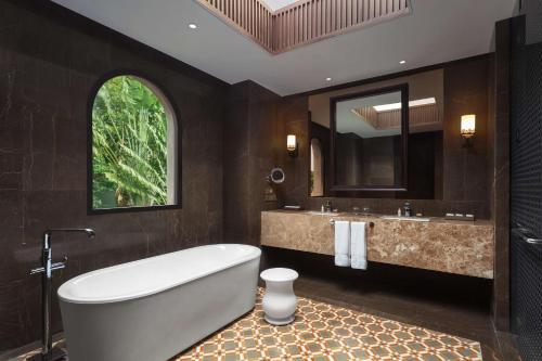 a bathroom with a tub and a sink and a mirror at Hilton Goa Resort Candolim in Candolim