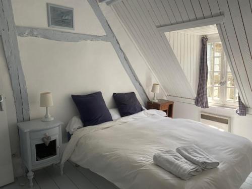 a bedroom with a large white bed with blue pillows at La Petite Fanny in Étretat