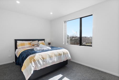 a white bedroom with a bed and a window at New 3bds house walk to Rototuna shopping Centre in Hamilton