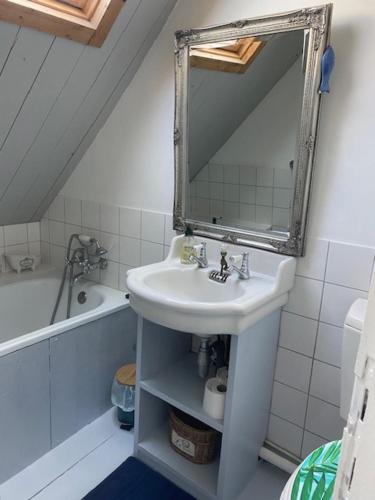 uma casa de banho com um lavatório, um espelho e uma banheira em La Petite Fanny em Étretat