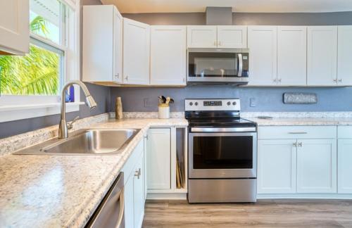 a kitchen with white cabinets and a stove and a sink at Henderson home in Sanibel