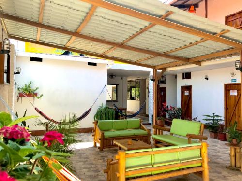 un patio con sillas verdes y pérgola de madera en Hostal Laurita Beach en Montañita