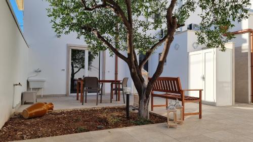 a bench sitting next to a tree next to a table at Uccio e Gina in Soleto