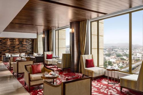 a restaurant with tables and chairs and large windows at Hilton Jaipur in Jaipur