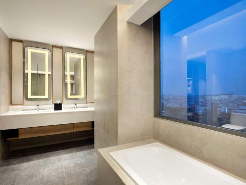 ein Badezimmer mit zwei Waschbecken und einem großen Fenster in der Unterkunft Hilton Garden Inn Jakarta Taman Palem in Jakarta