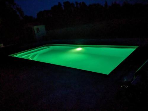 a green pool with a light in the dark at Climatisé, piscine chauffée et parking fermé in Brignac-la-Plaine