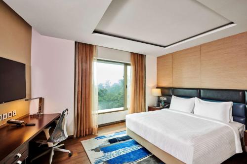 um quarto com uma cama, uma secretária e uma televisão em Hilton Garden Inn Lucknow em Lucknow