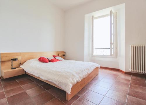 a bedroom with a bed with red pillows and a window at Borgo A Lago in Rezzonico