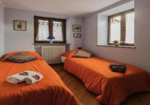 2 Betten in einem Zimmer mit orangefarbener Bettwäsche in der Unterkunft La Ca d'Piazi in Viù